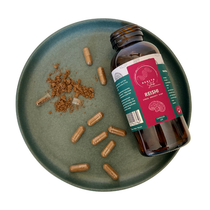 Bottle of Reishi supplement on a green plate with capsules and powder
